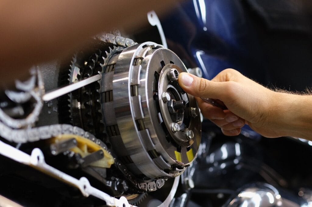 Mechaniker repariert Motor und Kette eines Motorrads